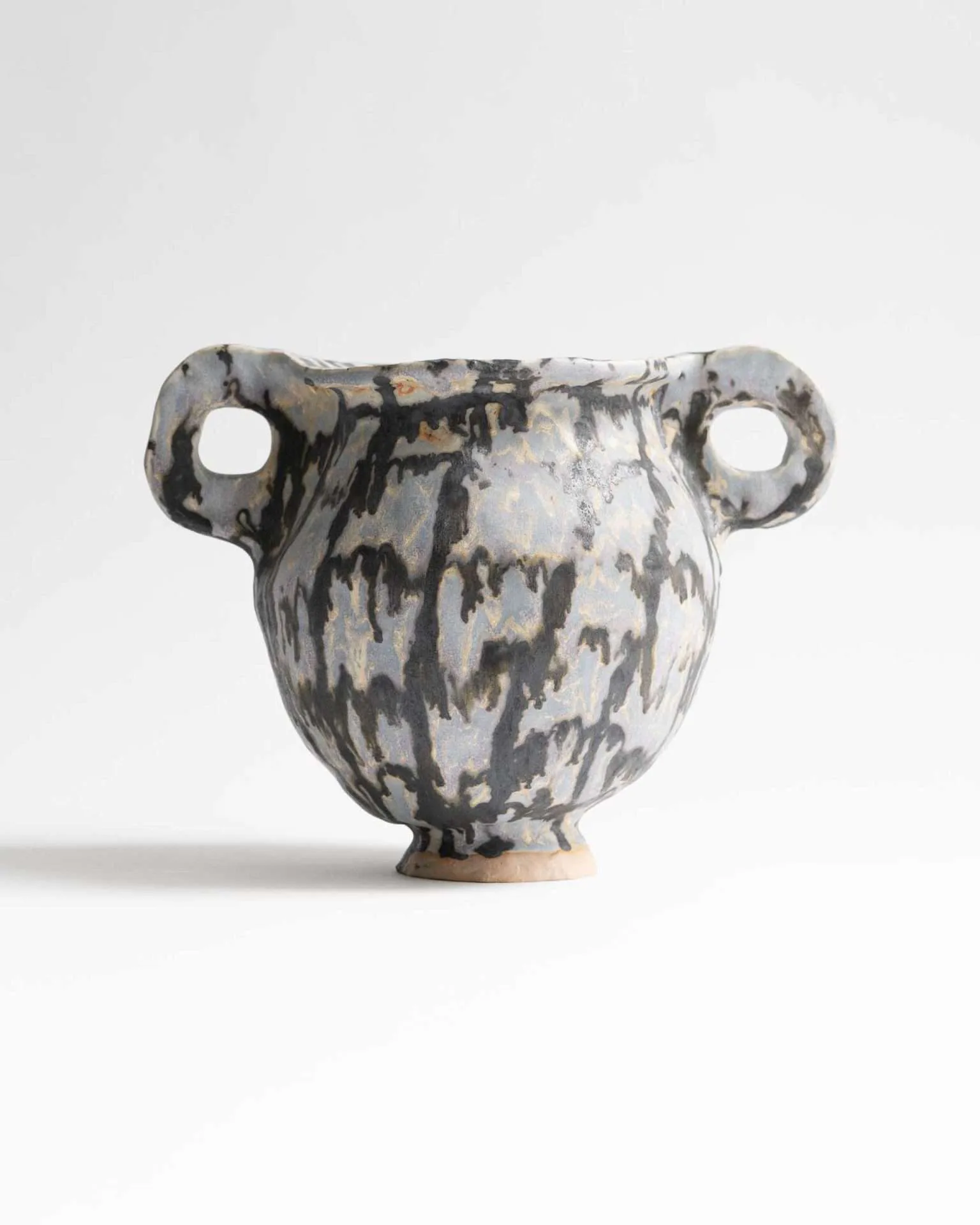 Sculptural ceramic vessel with organic wavy lines and concentric circle patterns in dark glaze with gold accents, angular form.