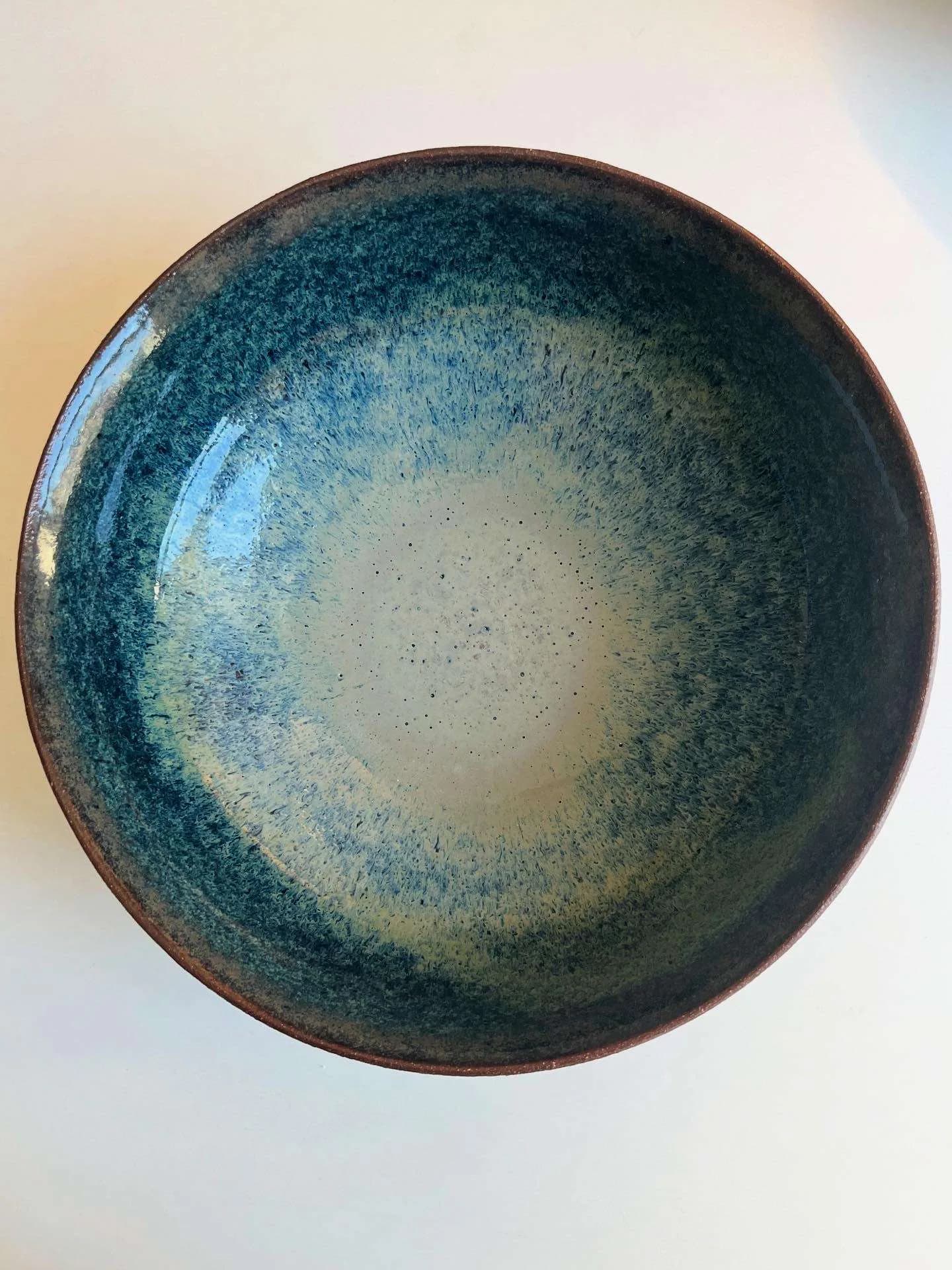 Single large ae stoneware ceramic bowl with speckled teal and cream matte glaze, rounded form with terracotta rim.