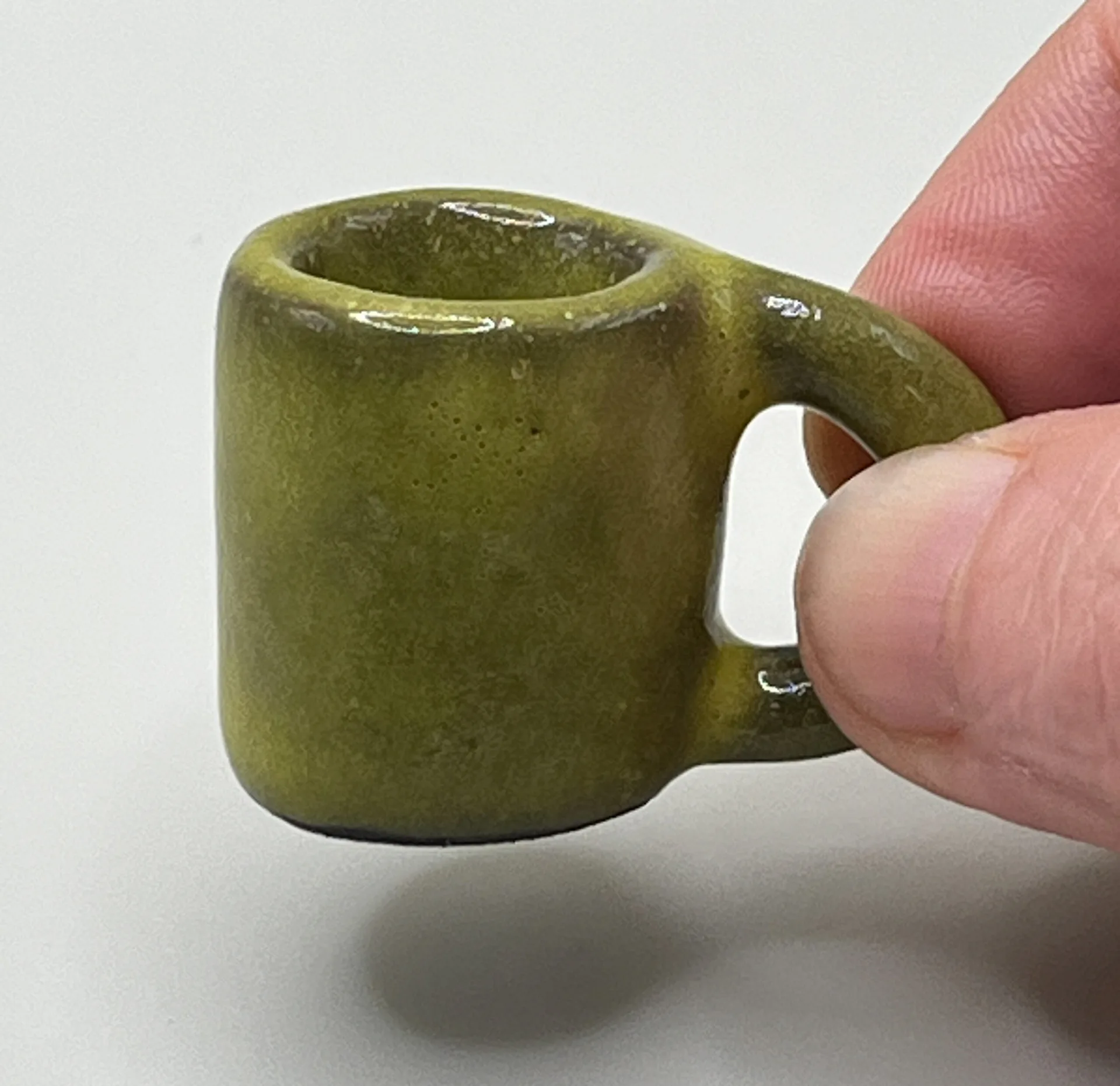 Olive green miniature ceramic mug with heart-shaped handle, clean product shot on white background