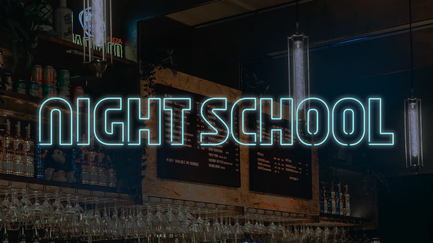 Neon sign installation reading 'NIGHT SCHOOL' in cyan blue lettering against dark storefront with metal framework.