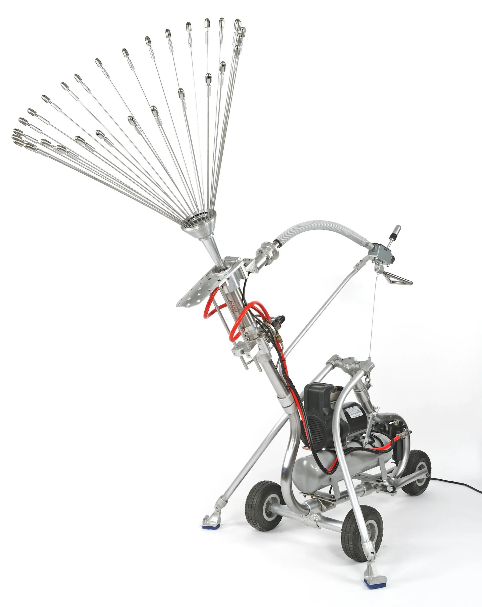 Spray-paint installation sculpture by Arnaldo Morales featuring radial array of metal tubes with motorized base on wheeled stand.