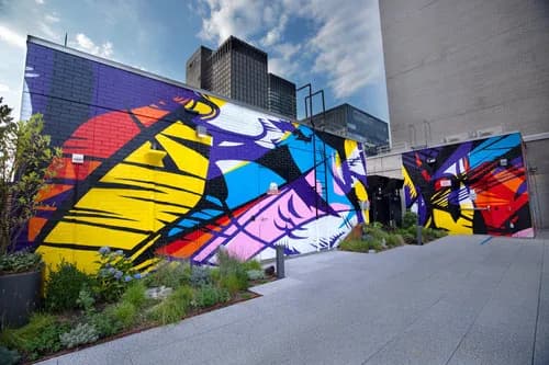 Large-scale colorful abstract mural on urban building exterior with bold primary color gestural forms