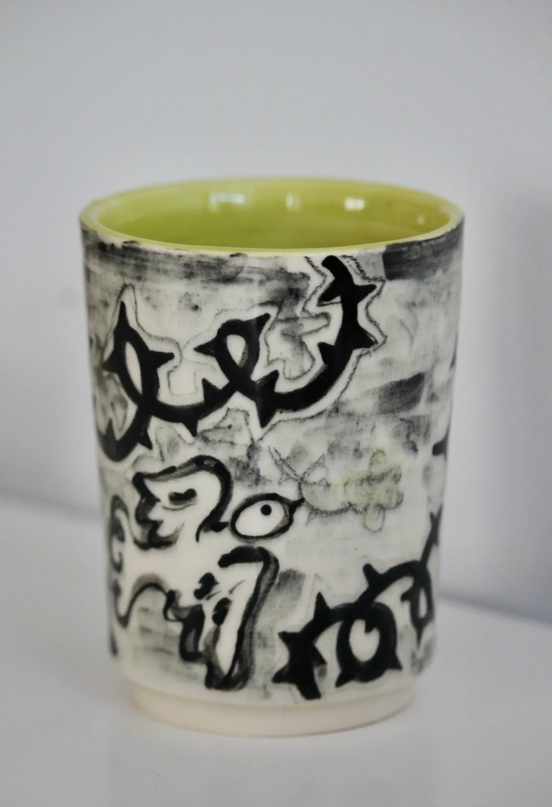 Ceramic tumbler with bold black sgraffito floral pattern and yellow interior glaze