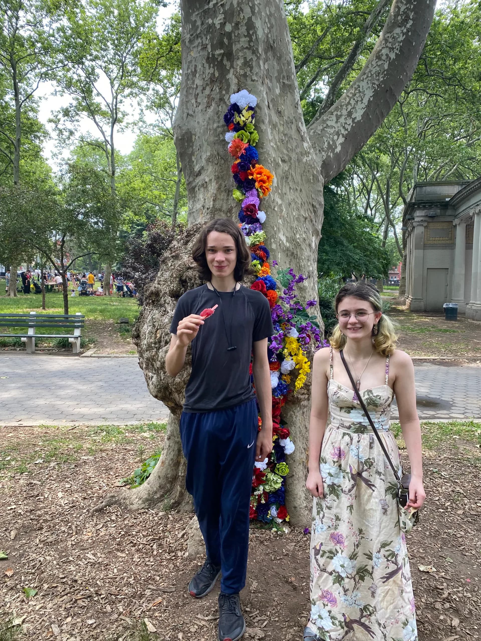Rainbow flower installation cascading along tree trunk with park and colonnade in background