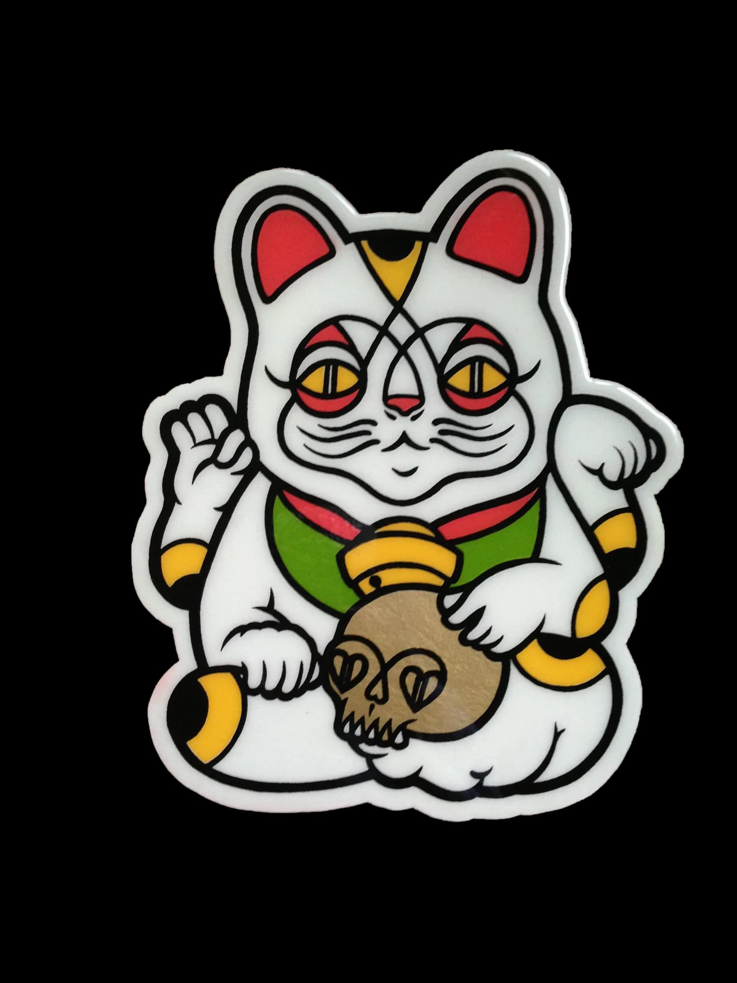 Sticker or die-cut design of a white Maneki-neko (lucky cat) with red ears, yellow accents, and holding a skull, rendered in bold line-art style.