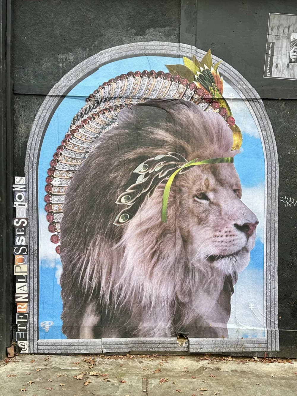 Mural in arched frame depicting a lion's head in profile wearing ornate feathered headdress and gold jewelry against blue sky background.
