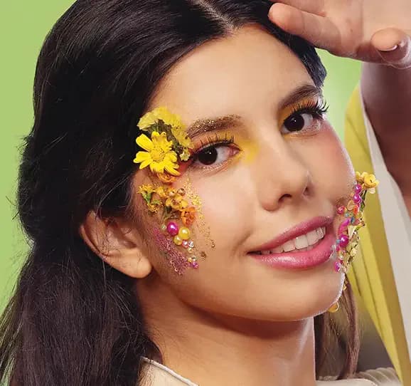 Model with floral and pearl face adornments and yellow eye makeup