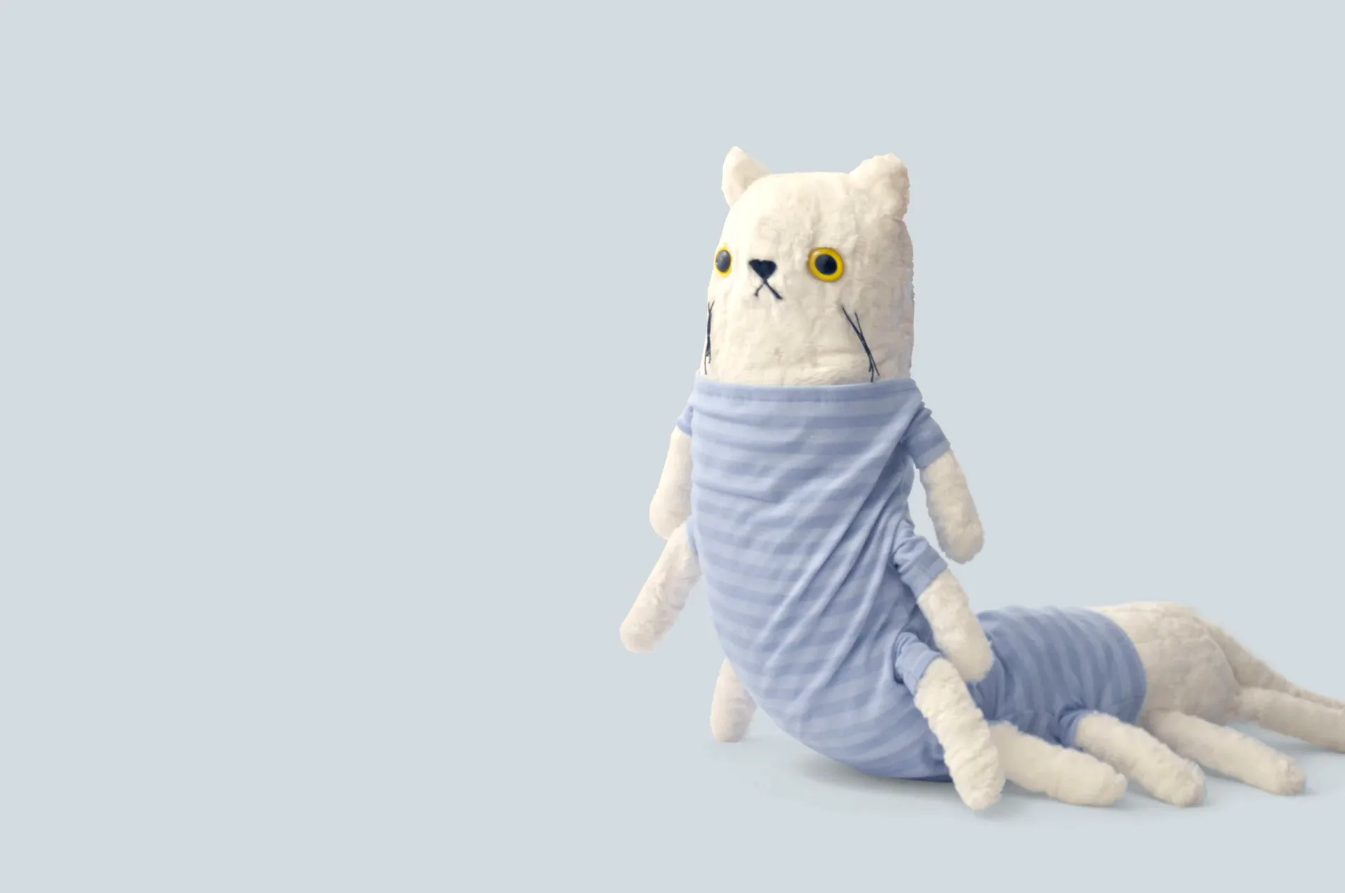 Handmade white cat plush toy with many legs wearing a blue striped shirt