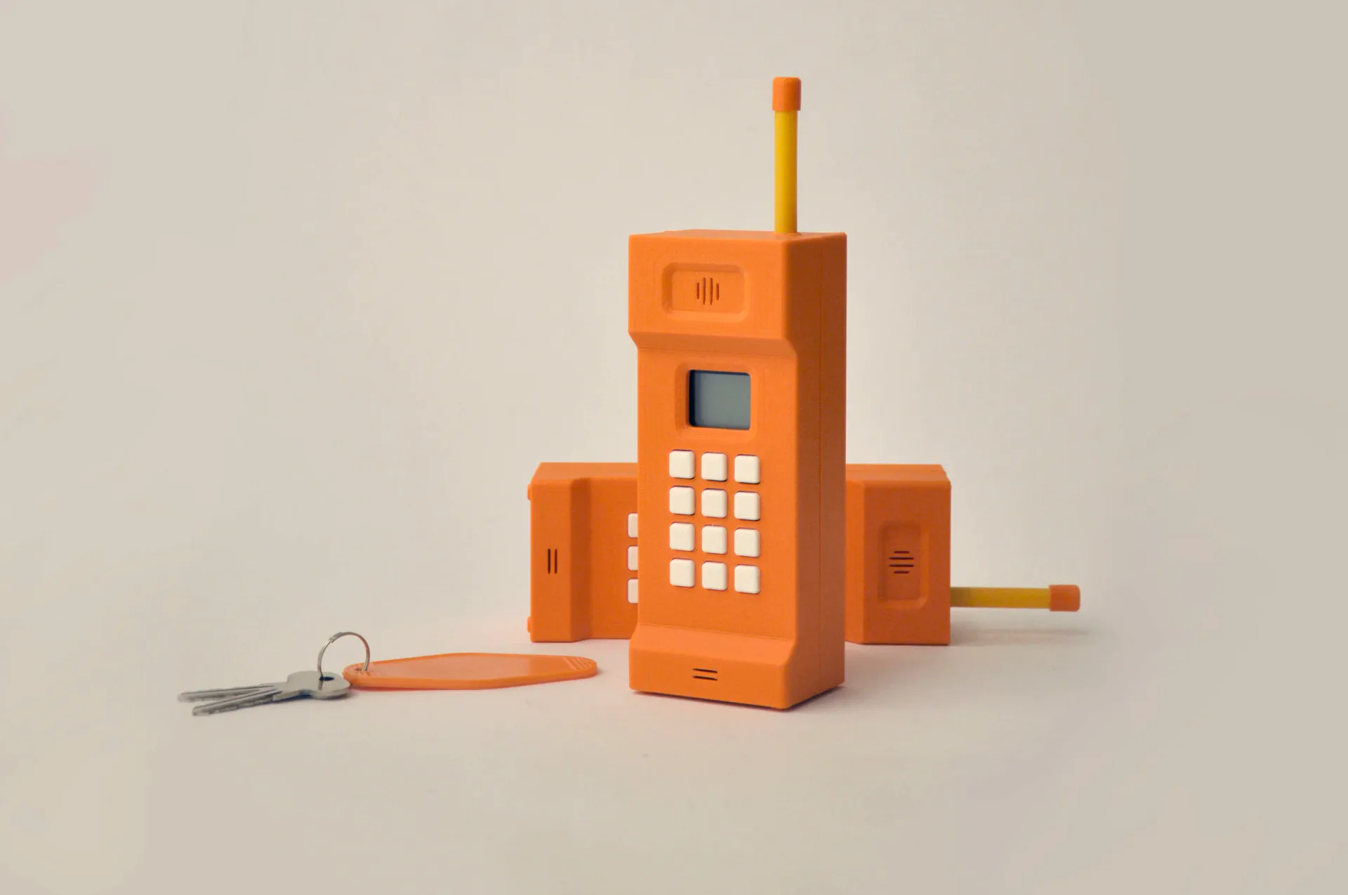 Orange 3D-printed retro brick phone sculpture with matching keychain and keys
