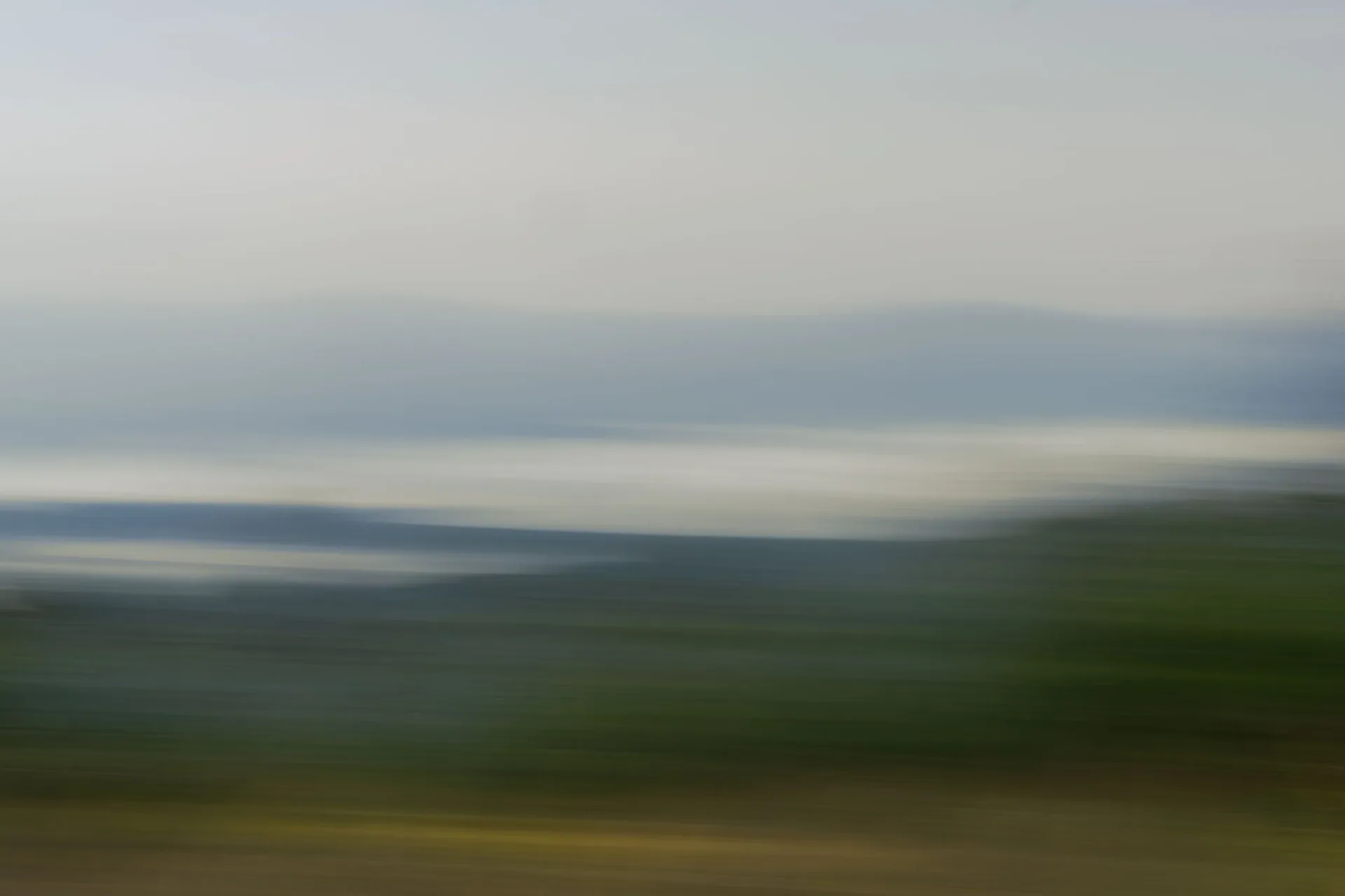 Abstract motion-blur landscape photograph with horizontal bands of green, blue and grey