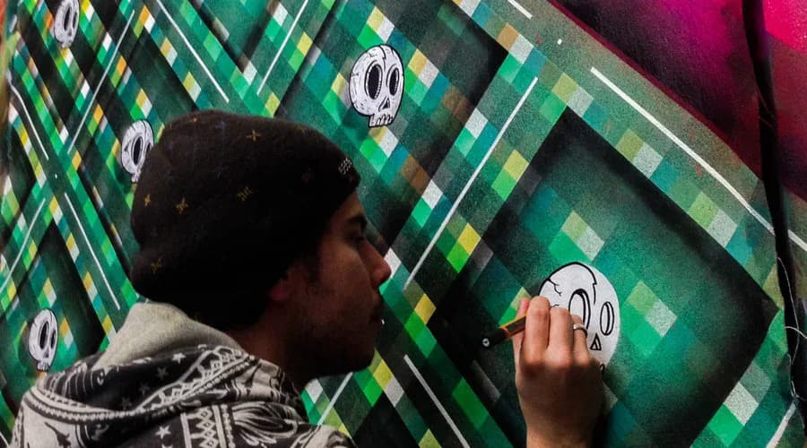 Person applying white sticker with skull icon to green and yellow diamond patterned wall surface.