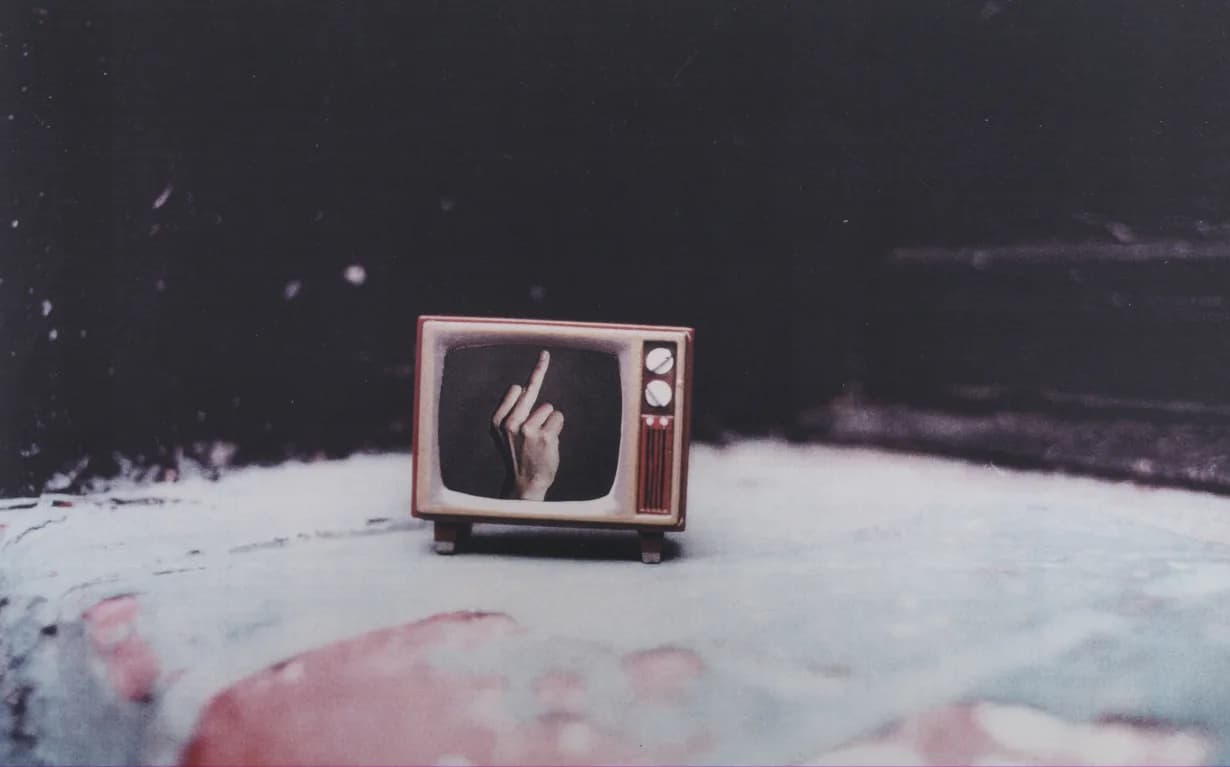 Vintage television set displaying a hand giving the middle finger, placed on a painted surface