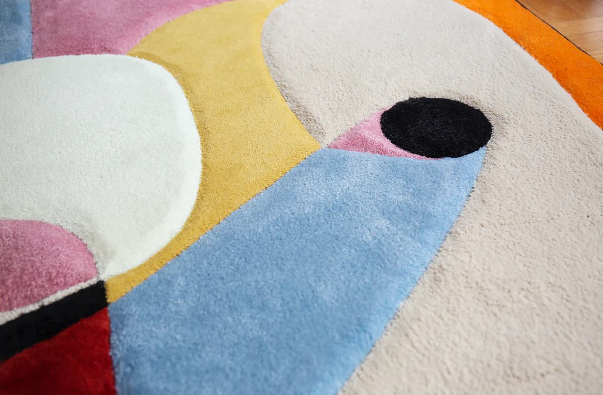 Close-up detail of a hand-tufted wool rug with abstract geometric shapes in pastel and bold colors