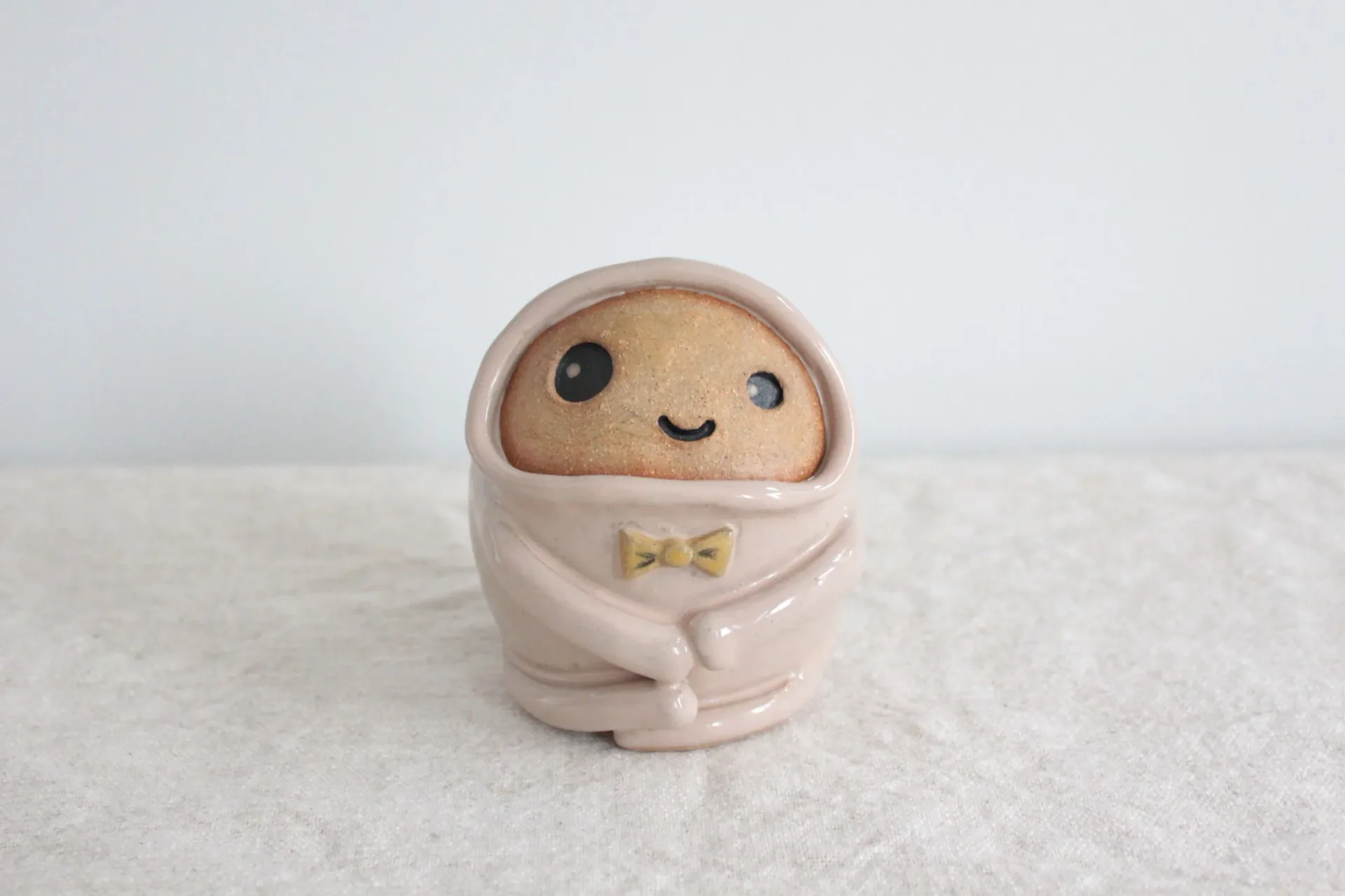 Sage green ceramic frog-creature figurine vase with lavender sprigs, glazed with bow tie detail