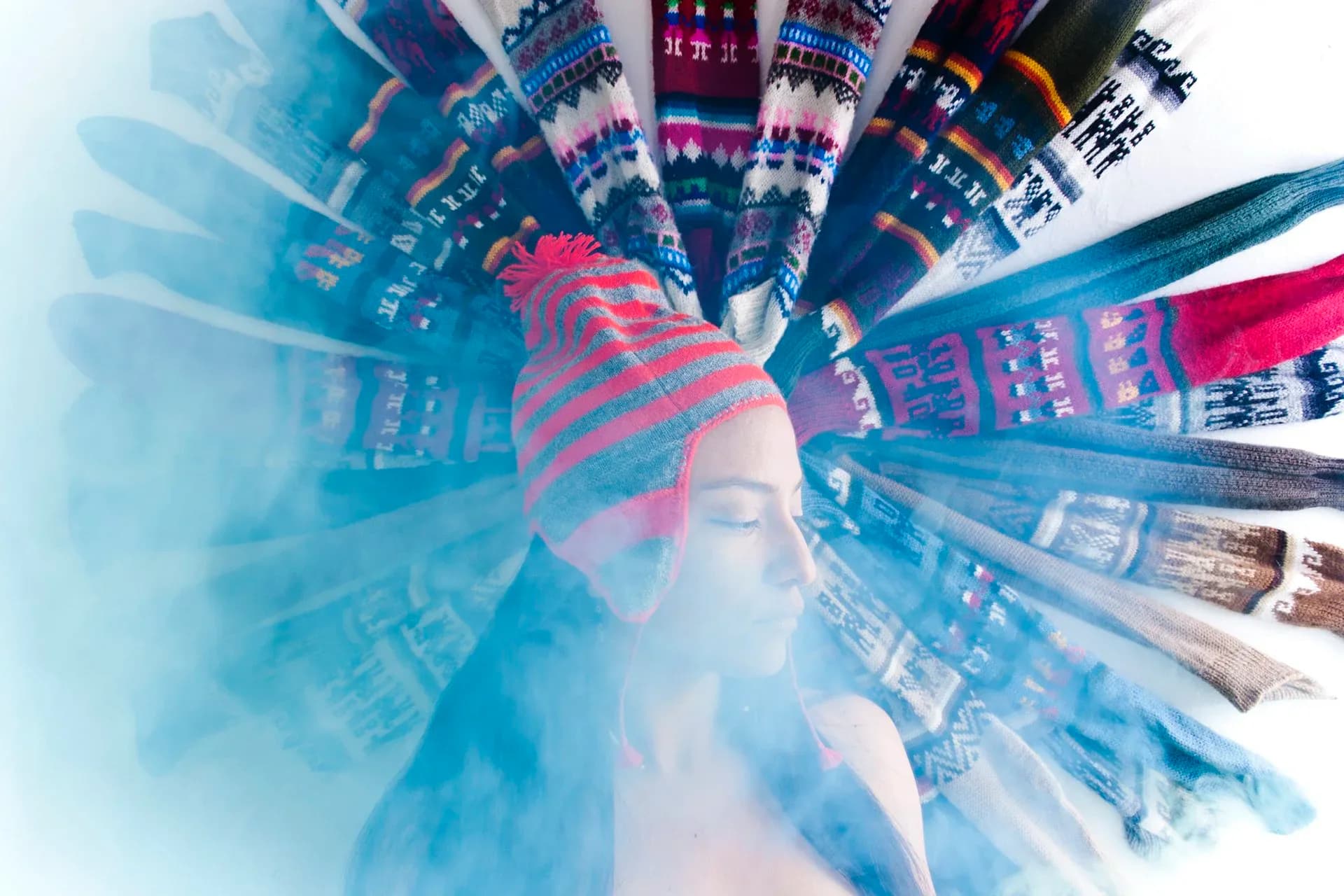 Conceptual photograph of figure surrounded by radially arranged colorful Andean textiles with blue smoke