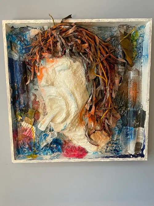 Mixed media assemblage with paper mache figure, dried leaves, collaged newspaper, and paint in a box frame