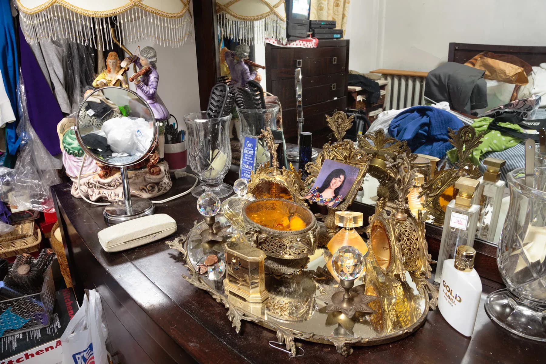 Ornate golden vanity or display surface cluttered with jewelry, perfume bottles, and personal items in warm metallic tones.