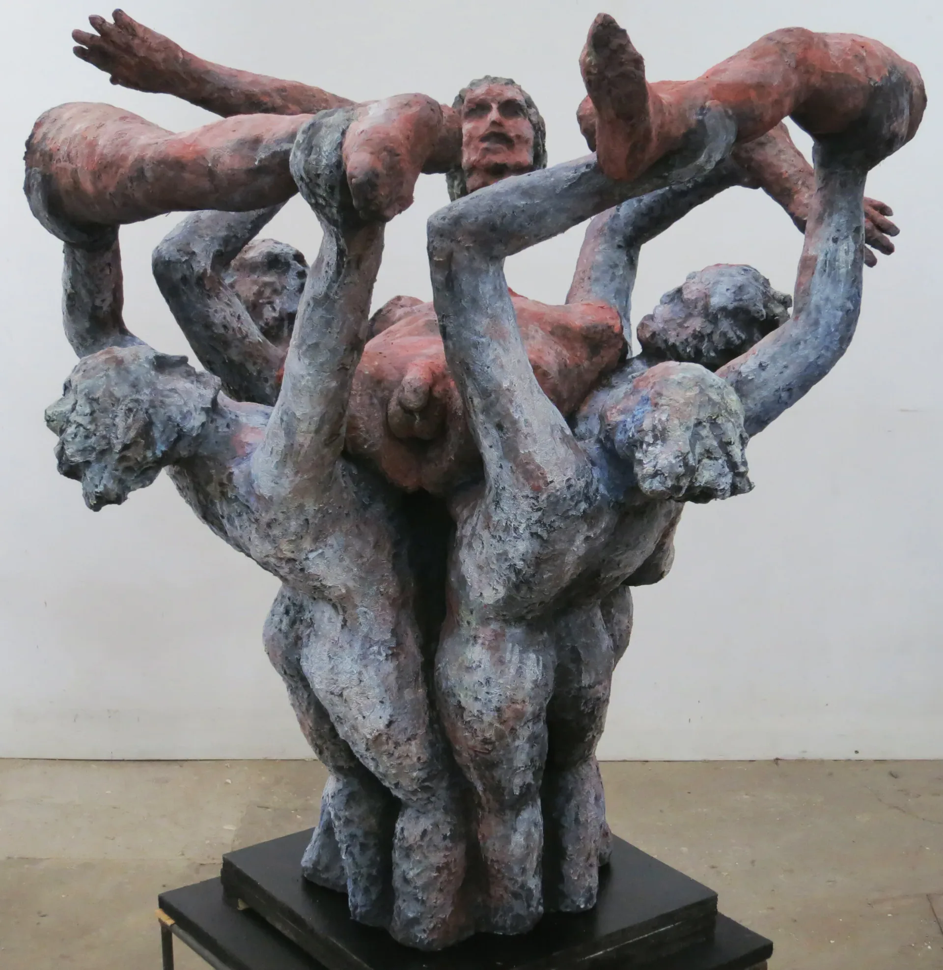 Large multi-figure sculpture of intertwined bodies in blue and red tones