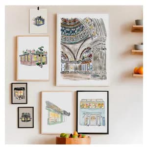 Gallery wall arrangement of framed architectural illustrations and drawings by Jen Toth, including building facades and interior spaces.