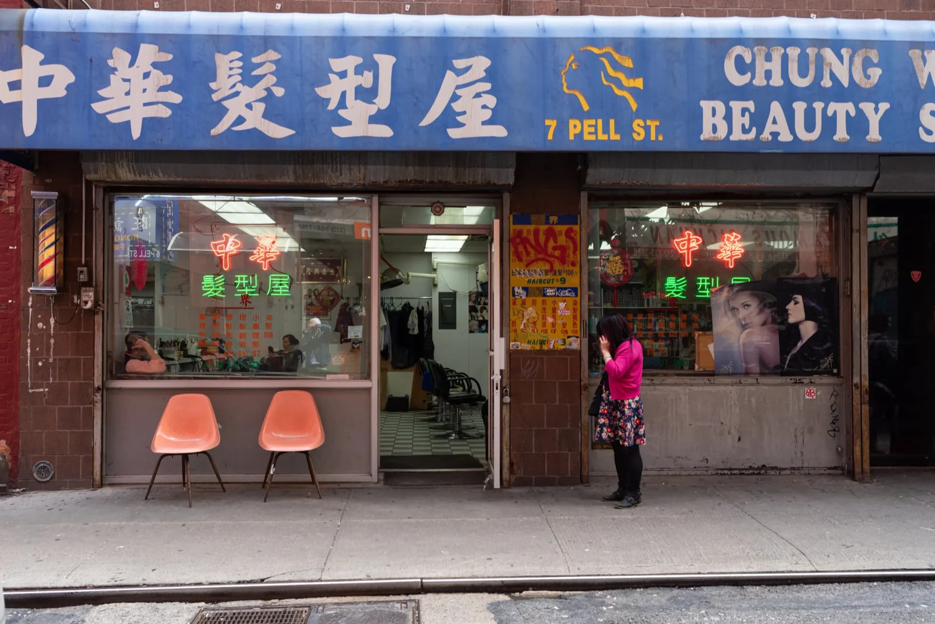 Chinatown beauty salon storefront with neon signs and orange chairs