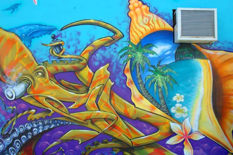 Vibrant mural by Johnny Alamo featuring a colorful octopus and tropical island scene with palm trees, bright blues, oranges, yellows, and purples in mixed-media street art style.