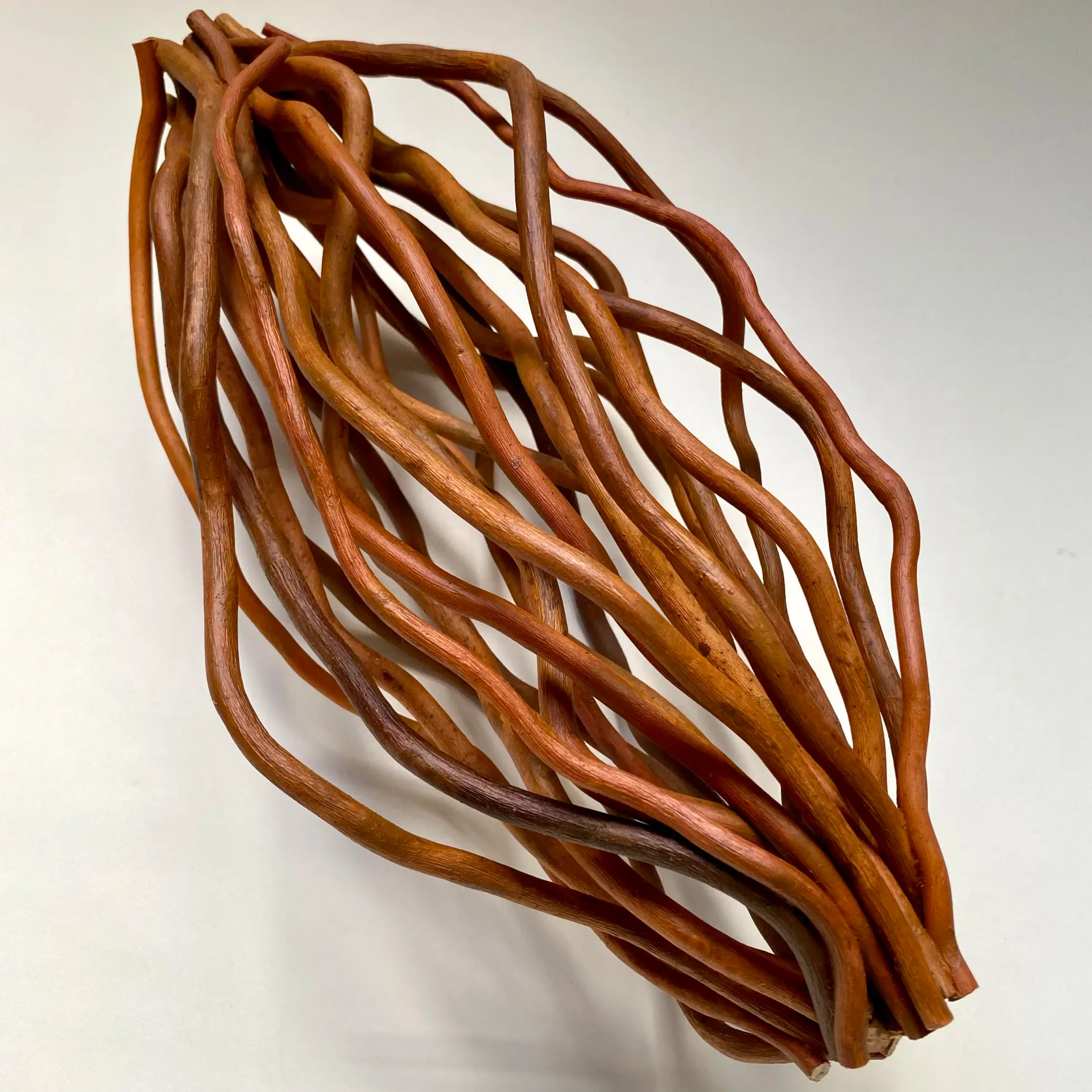 Large open woven sphere of wavy terracotta-colored branches on white background