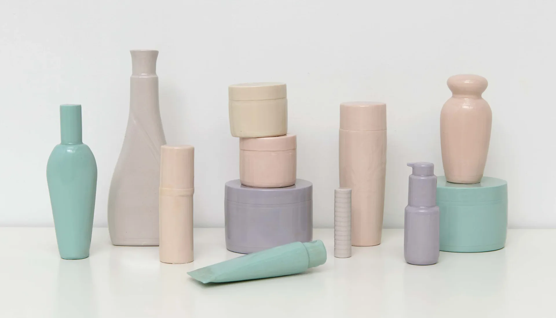Group of pastel ceramic sculptures mimicking cosmetic bottles and containers