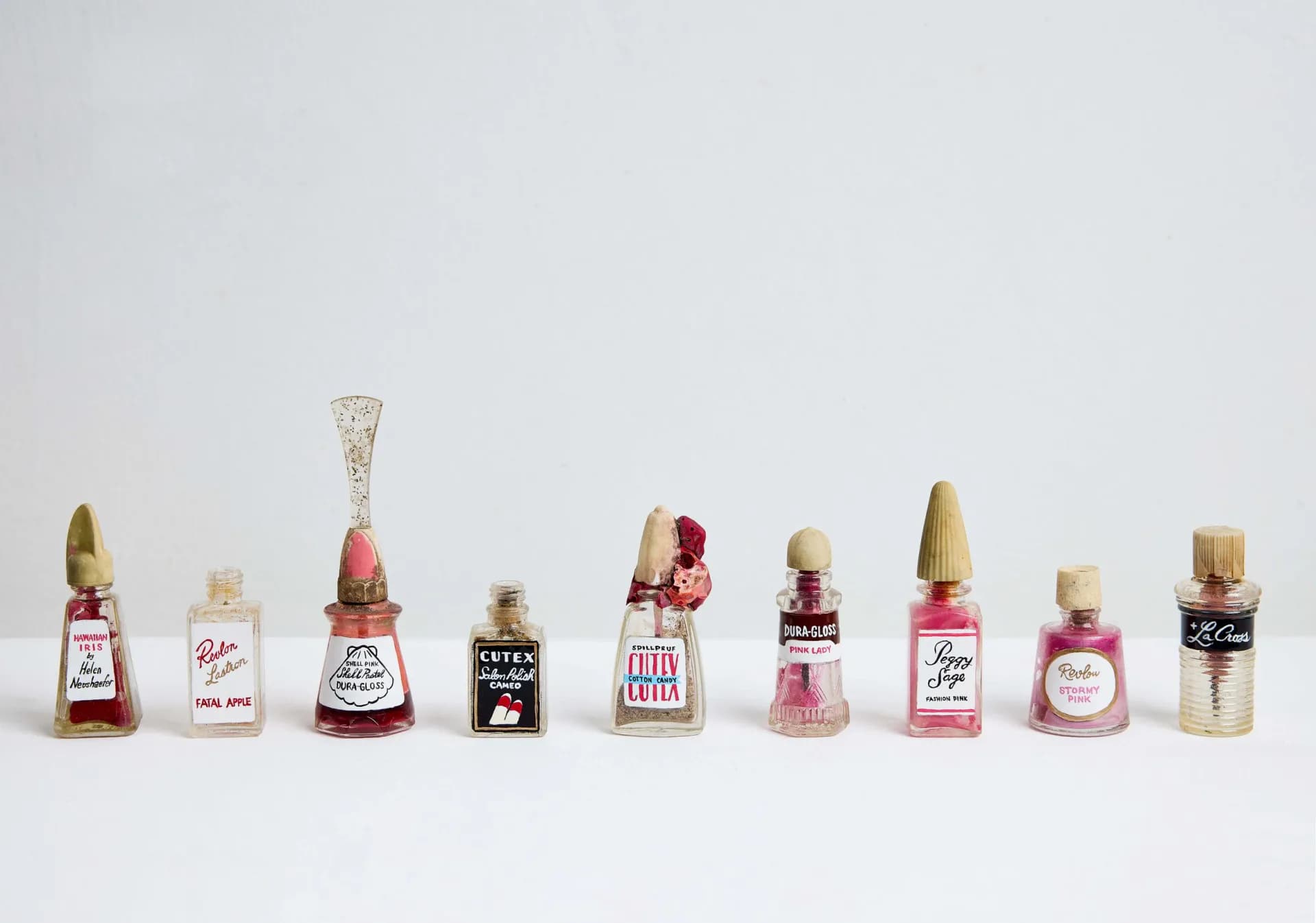 Row of vintage nail polish bottles with original labels on white surface