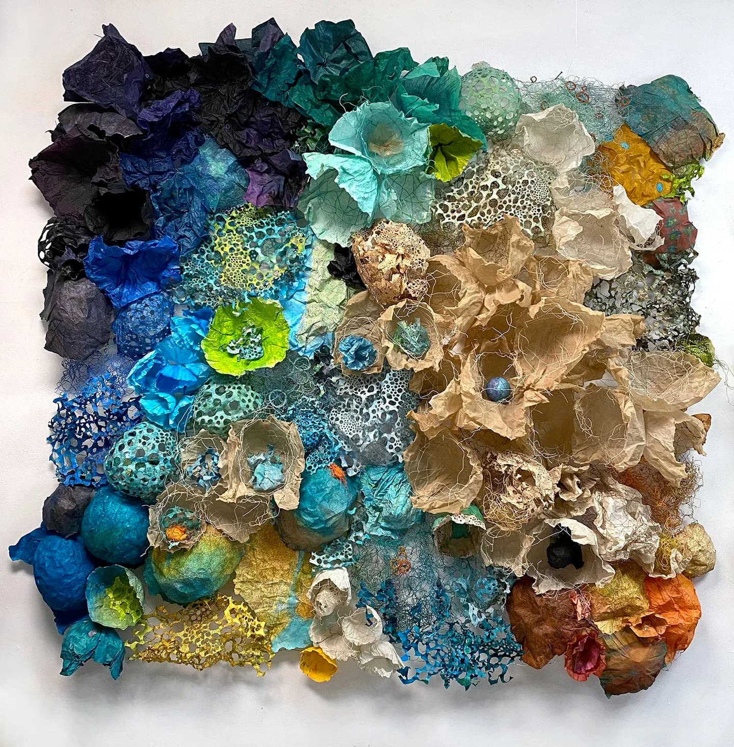 Square paper sculpture wall panel with yellow, green, teal, and purple organic floral forms