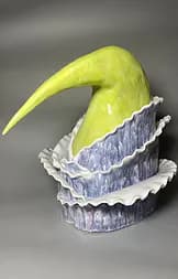Yellow-green ceramic horn sculpture rising from layered blue-grey ruffled base