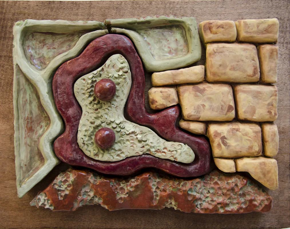 Glazed ceramic relief sculpture with biomorphic and brick-like forms in red, green, and ochre tones