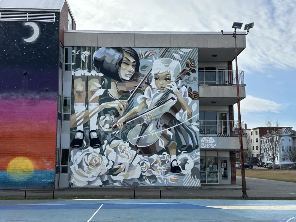 Multi-story building mural featuring a monochromatic figure surrounded by abstract mechanical and organic forms, with a gradient sunset panel on the left side.