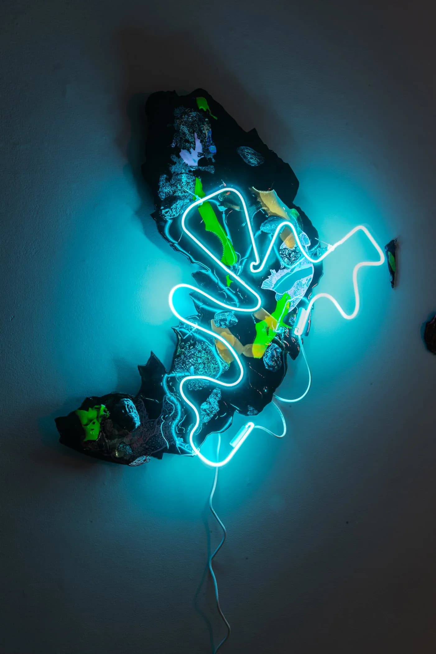 Large neon and mixed-media wall sculpture with cyan light on dark textured base
