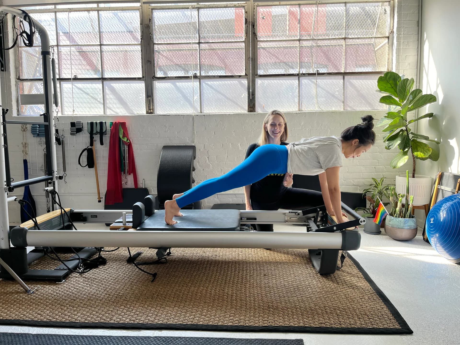 Instructor assisting client performing a leg extension on the Pilates reformer