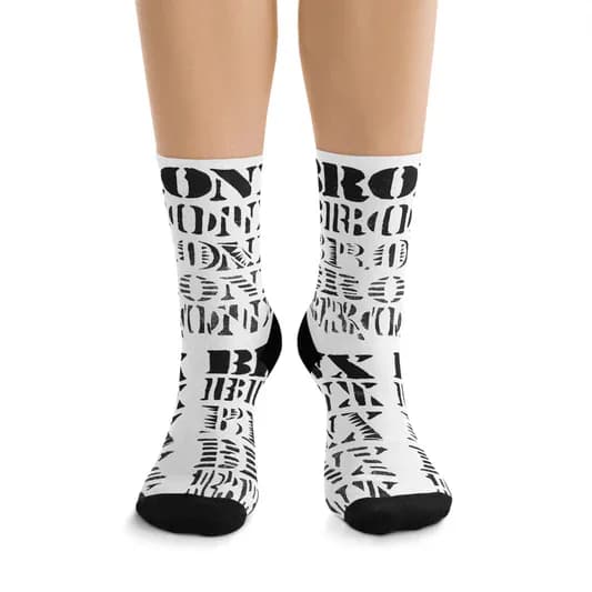 Crew socks with black and white allover text pattern featuring fragmented typography and letters, black heel and toe.