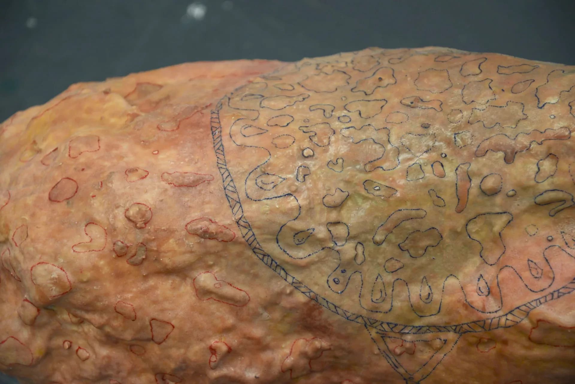 Large red flame-shaped hanging installation made of layered cut acrylic panels suspended by chains