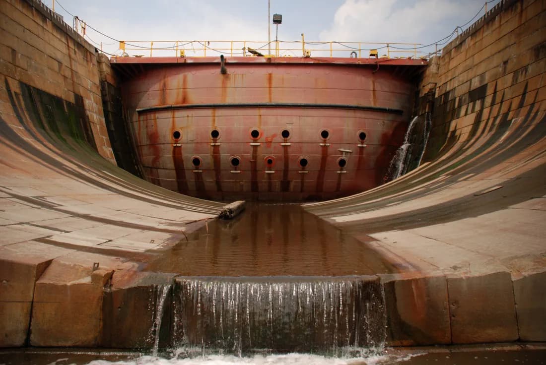 Ship hull in dry dock with water cascading over stone walls