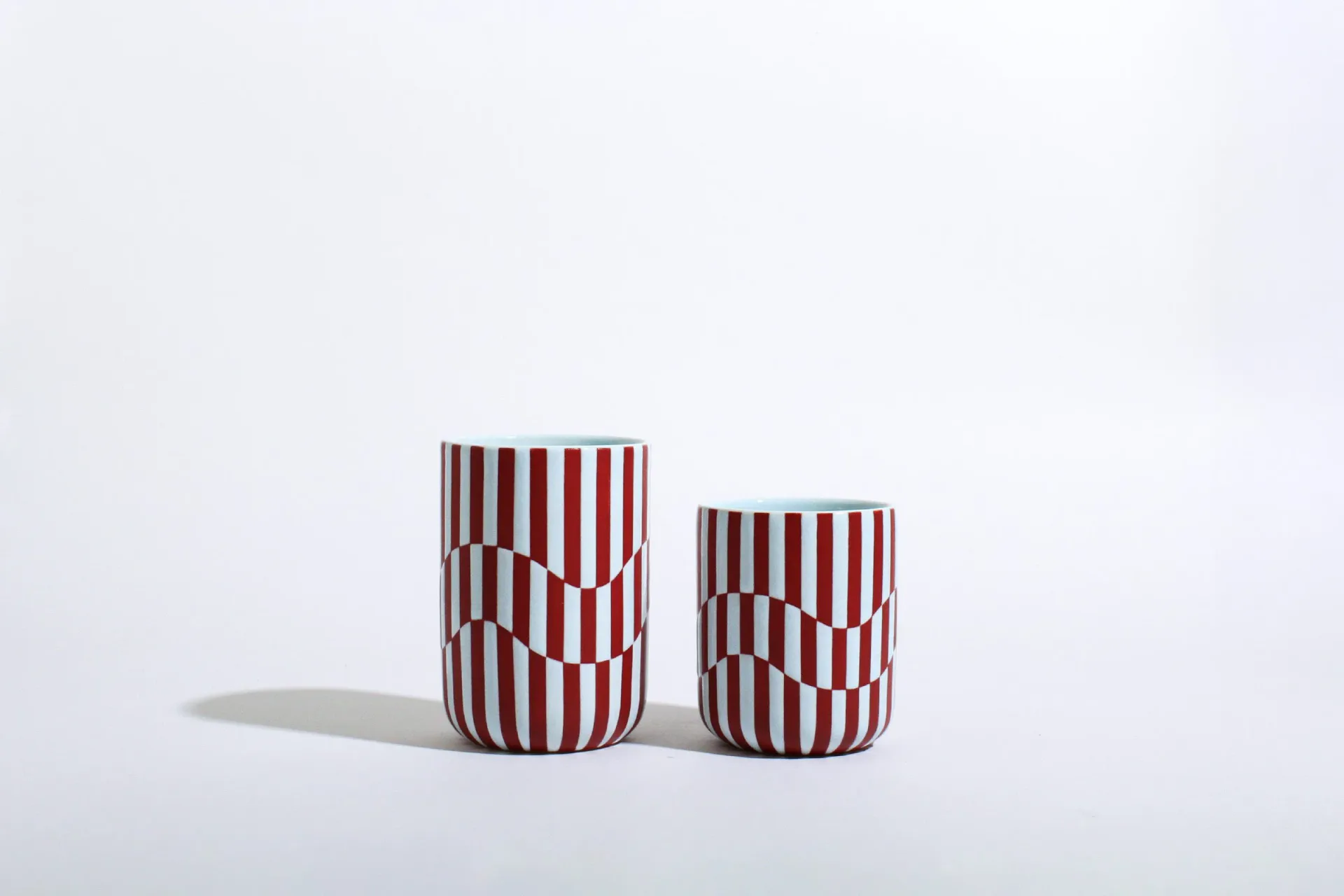 Two ceramic cups with op-art burgundy and sky blue striped wave pattern