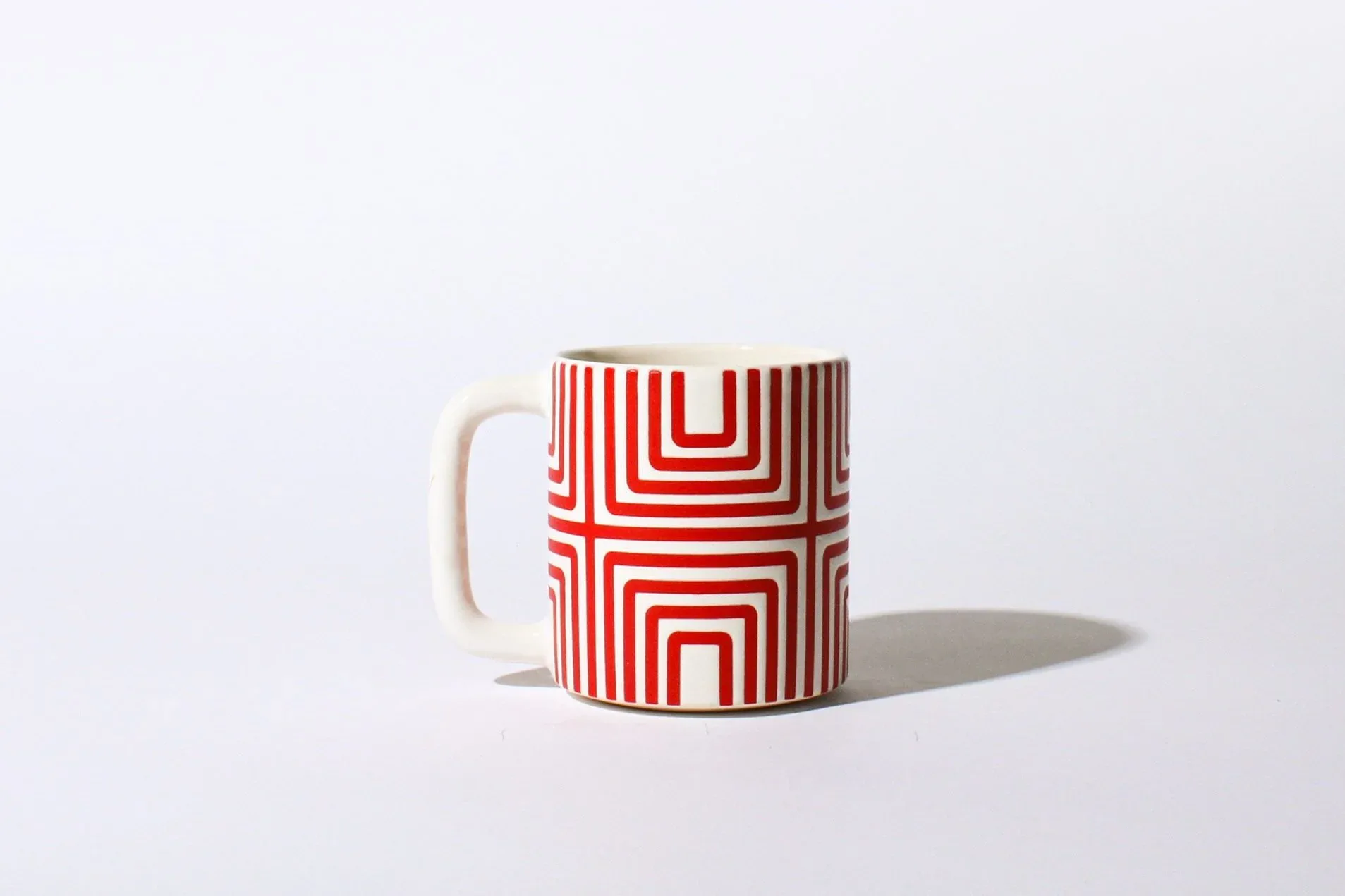 Single ceramic mug with bold red concentric square labyrinth pattern