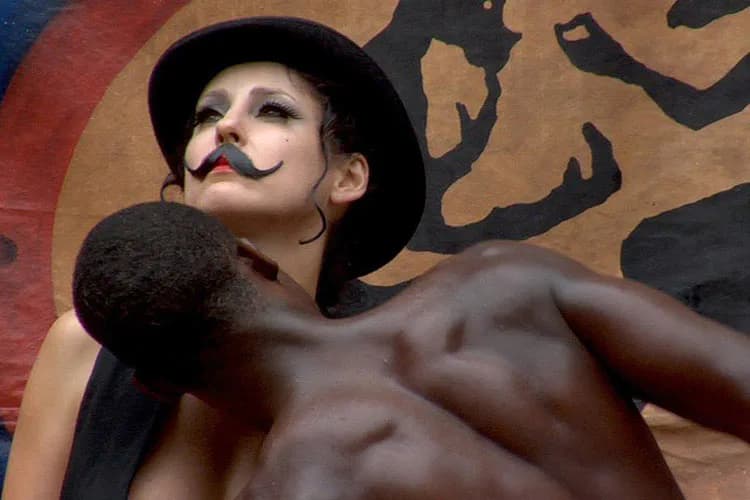 Shirtless figure wearing black hat and false mustache against abstract brown and black painted backdrop; mixed-media photograph with surrealist aesthetic.