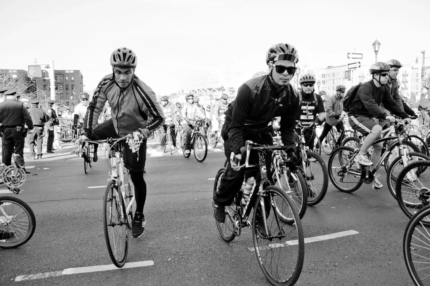 Black and white photograph of cyclists riding on a street during what appears to be a community bike ride or protest.