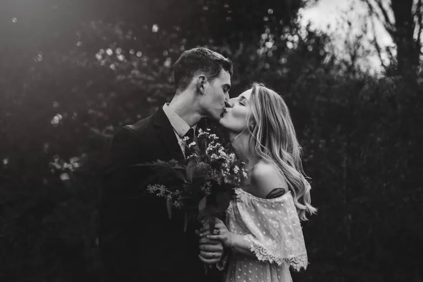 Couple kissing in black and white with wildflower bouquet