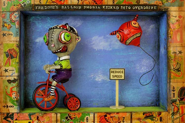 Mixed-media assemblage featuring a red tricycle with stacked mechanical robot heads and a red flying object against a blue sky backdrop, surrounded by colorful patterned border.