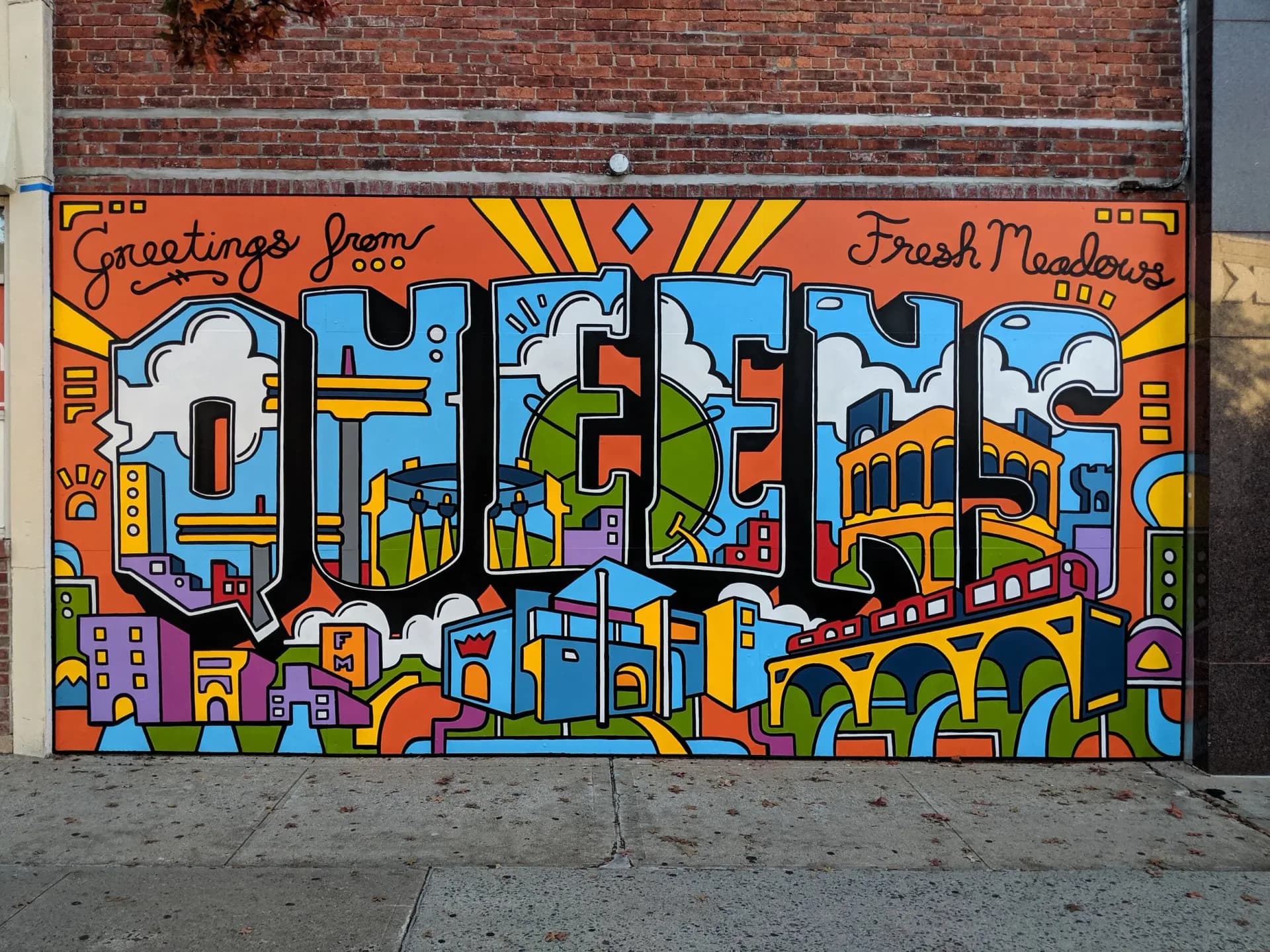 Large-scale mural on brick featuring 'GREENE' in bold blue letters with colorful geometric patterns, cityscapes, and 'Fresh Meadows' framing.