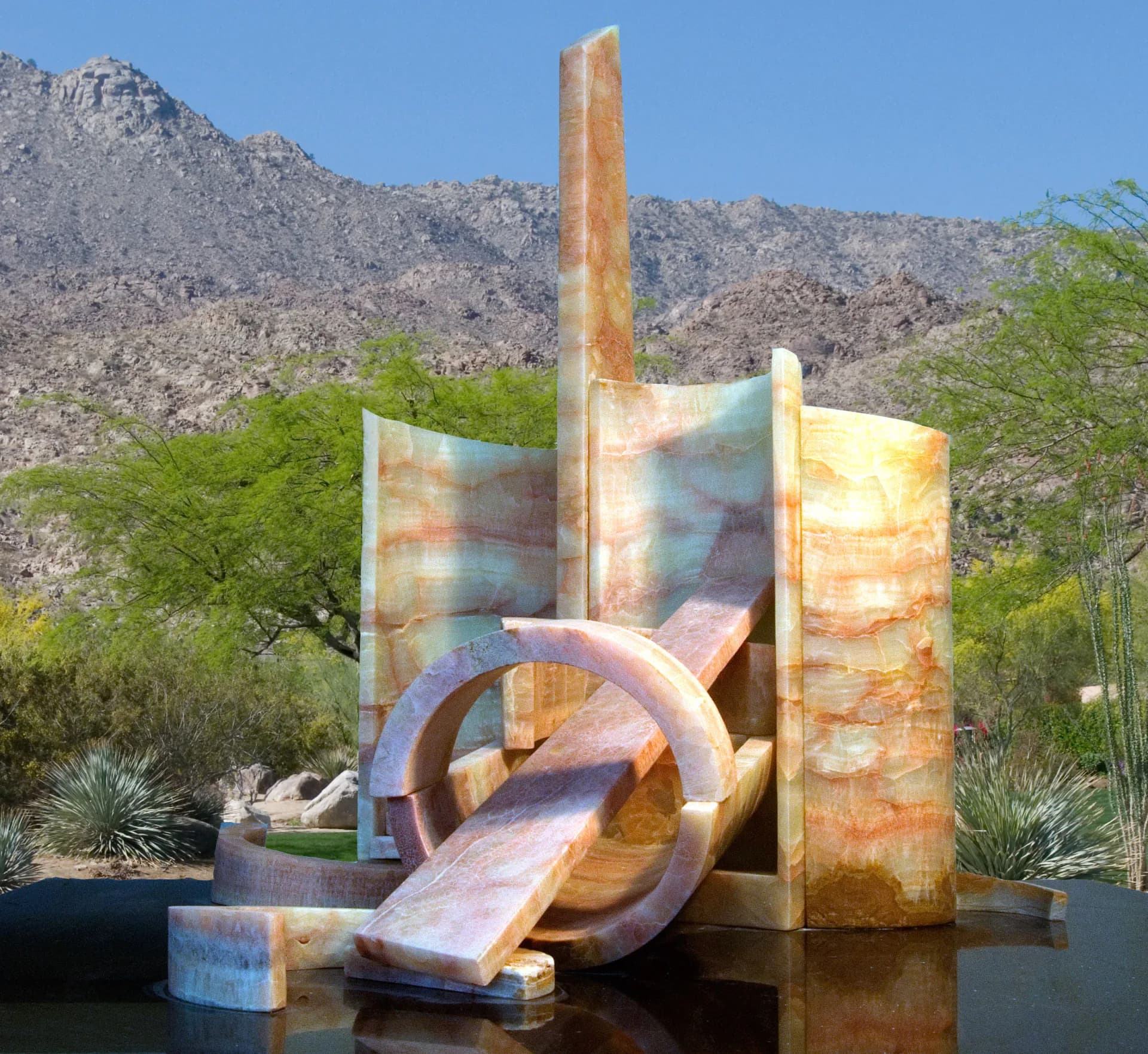 Large onyx and glass abstract sculpture with circular ring element in desert landscape