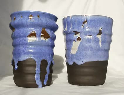 Two ceramic tumblers with blue drip glaze over dark stoneware