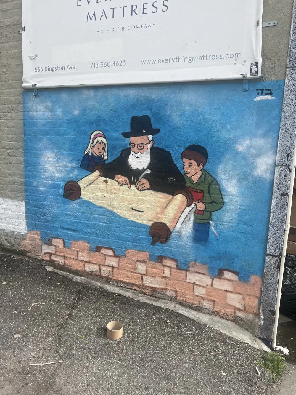 Mural on blue background depicting an elderly bearded man in a hat and two children unrolling a large scroll or blueprint, with red brick texture at bottom.