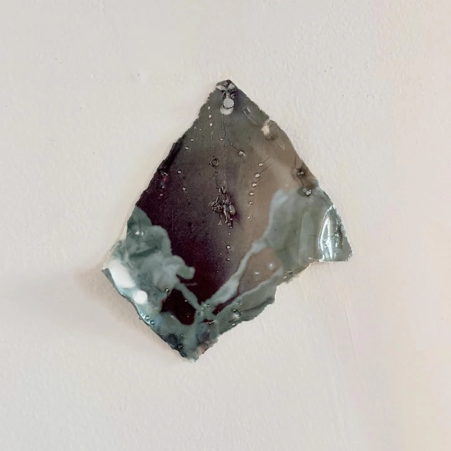 Small ceramic sculptural form with dark glaze, organic angular shape with contrasting pale glazed sections.