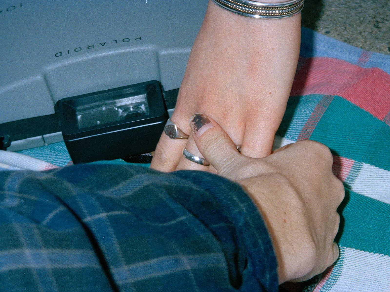 Person's hand and arm wearing rings, holding fabric near a document scanner on patterned textiles.