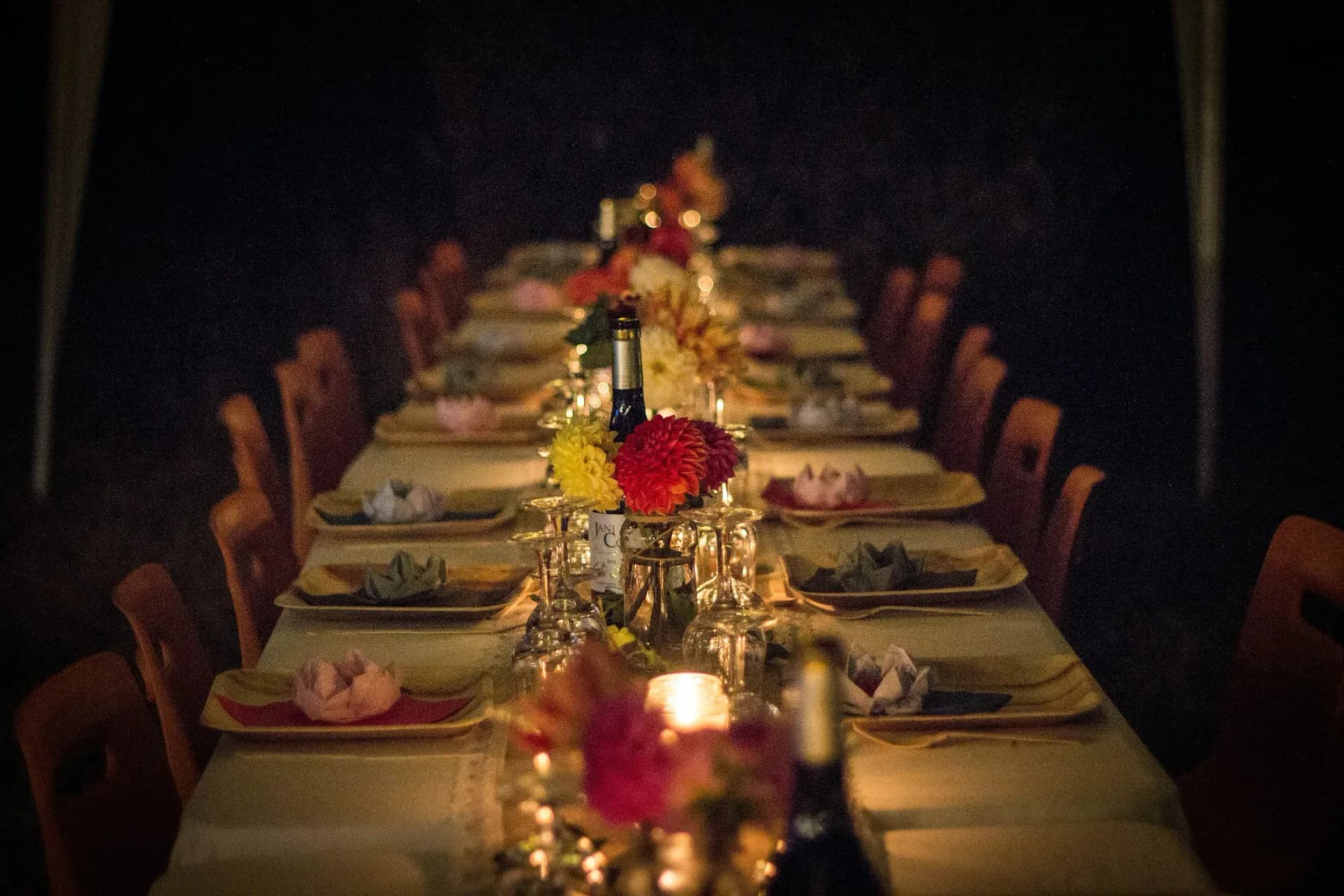 Elegantly set long dinner table with candles and floral centerpieces in warm light